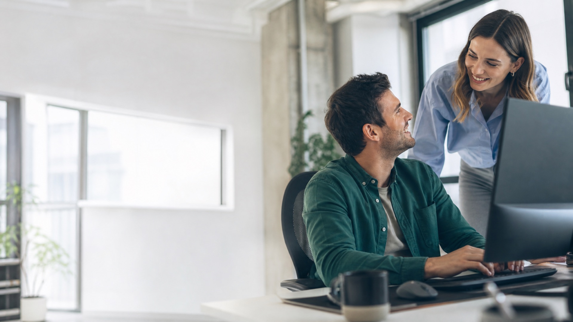 Two creative strategists collaborating happily at a computer in a bright studio